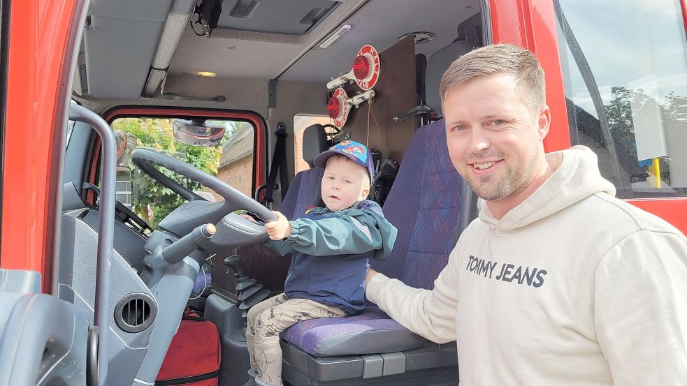 Probesitzen bei der Wremer Feuerwehr: Während sich Papa Marcel Bursky über eine großzügige Spende freut, blüht Söhnchen Theo auf dem Fahrersitz des Feuerwehreinsatzwagens auf. Foto: Heike Leuschner