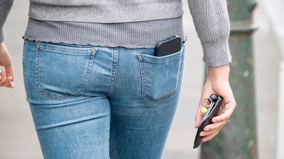 Manche tragen das Handy in einer der hinteren Hosentaschen. Doch ist das die beste Variante? Foto: IMAGO/Michael Gstettenbauer