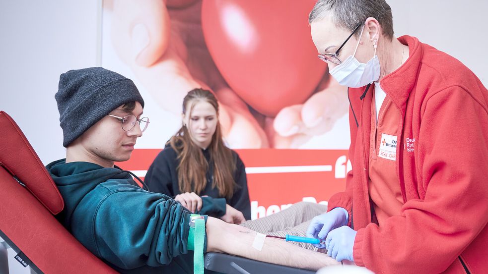 Schwester Christina (rechts), Teamleiterin beim Deutschen Roten Kreuz (DRK) nimmt von Spender Artjom Blut ab, während seine Freundin Laura neben ihm sitzt. Foto: Annette Riedl/dpa