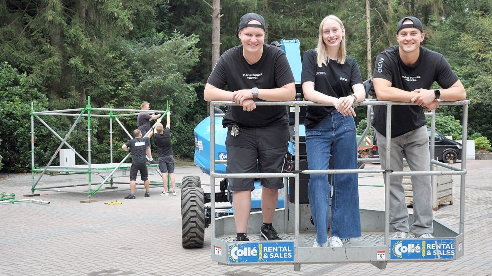 Moritz Radde (von links), Marah Schön und Jonah Eschen vom Wiesmoorer Generationenverein machen fürs Planet Future Festival aus der Freilichtbühne einen Open-Air-Tanzpalast. Im Hintergrund entsteht die Hauptbühne. Foto: Ullrich