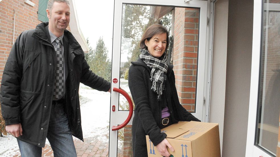 Hereinspaziert und herzlich willkommen: Anfang Dezember 2010 hält Groß Berßens Bürgermeister Reinhard Kurlemann HanBG-Geschäftsführerin Corinna Kuhny die Tür ins Dorfgemeinschaftshaus aus. Sie trägt einen Karton mit dem Grundstock der HanBG-Akten. Foto: Tim Gallandi