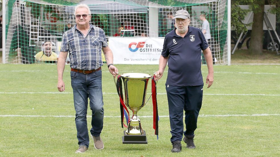 Jedes Jahr lassen sich die Organisatoren etwas Neues einfallen. In diesem Jahr trugen die Vereinslegenden Otto Löning (links, SV Wallinghausen) und Heiko Feddermann (TuS Esens) den Siegerpokal beim Eröffnungsspiel in Wallinghausen auf den Platz. Foto: Gronewold