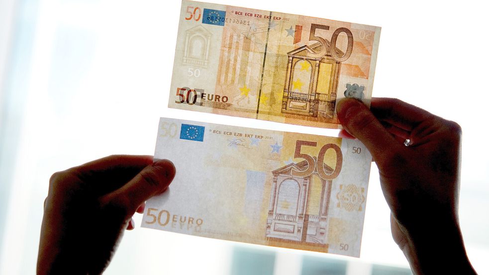 Ein echter und ein falscher Fünfzig-Euro-Schein werden gegen das Licht gehalten. Foto: Franziska Gabbert/DPA-Zentralbild/DPA
