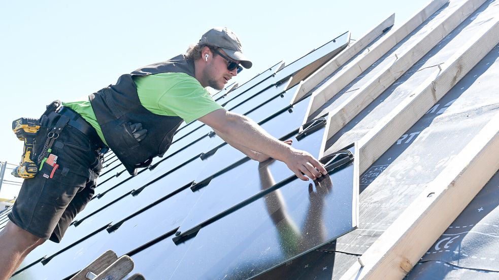 Handwerker arbeiten an einem Photovoltaik Dach. Die neuartige PV Anlage besteht aus Photovoltaik Modulen in Form von Dachplatten. Foto: Bernd Weißbrod/dpa