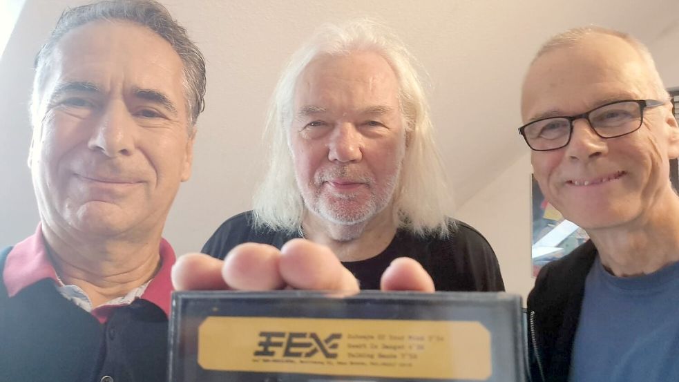 Die Musiker der in den 1980er-Jahren gegründeten Kieler Band FEX – Michael Hädrich (von links), Ture Rückwardt und Norbert Ziermann – halten ein altes Demotape. Die Musiker sind die Urheber eines Liedes, das im Internet jahrelang Rätsel aufgab und dort als „The most mysterious Song of the Internet“ galt. Foto: Ture Rückwardt/Fex/dpa