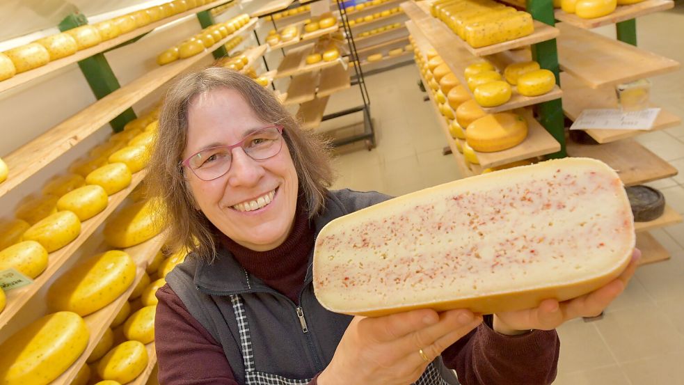 Claudia Berkhout zeigt den Verkaufsschlager: Pilsumer Leuchtturmkäse. Mit seinen roten Streifen erinnert er an das ostfriesische Wahrzeichen auf dem Deich. Foto: Ortgies