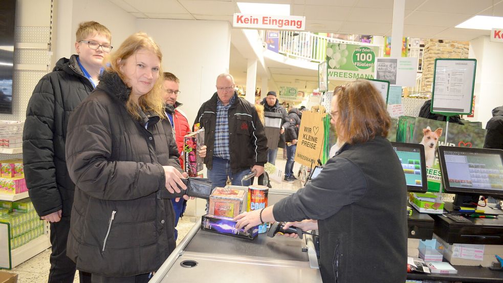 Karin Vehndel aus Backemoor steht mit ihrem 15-jährigen Sohn Nico an der Kasse des Wreesmann-Aktionshauses. Dort verkauft ihnen Johanna Büter Silvesterfeuerwerk. "Das Geschäft läuft bombig", versichert sie. Foto: Fertig