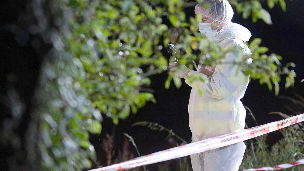 Ein Mitarbeiter der Spurensicherung arbeitet im Umfeld des Leichenfundortes. Foto: Swen Pförtner/dpa