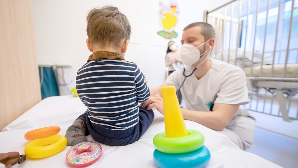 Ein Arzt untersucht in einer Kinderklinik ein Kind auf Grippe-Symptome. Foto: Gollnow/DPA