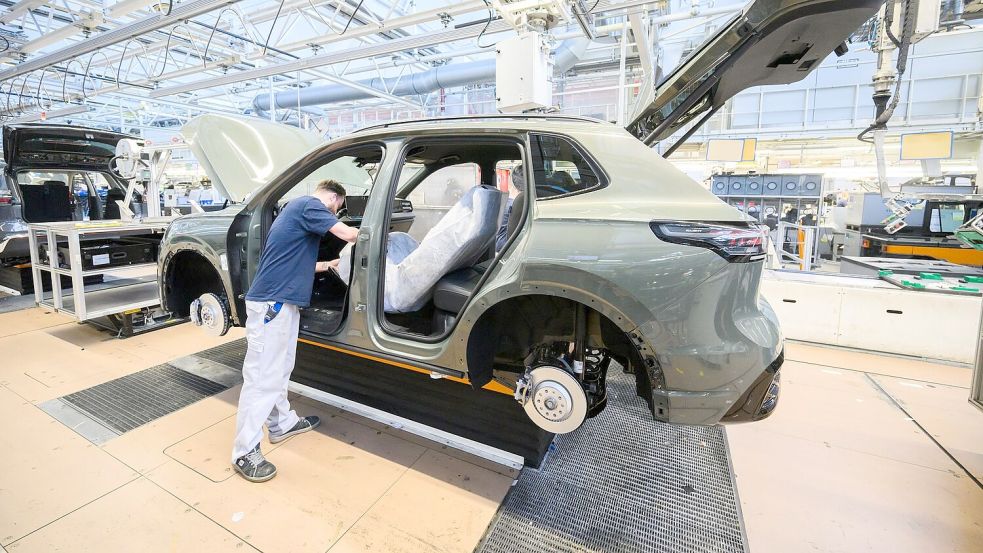 Mitarbeiter montieren in Wolfsburg den VW Tayron. (Archivbild) Foto: Julian Stratenschulte/dpa