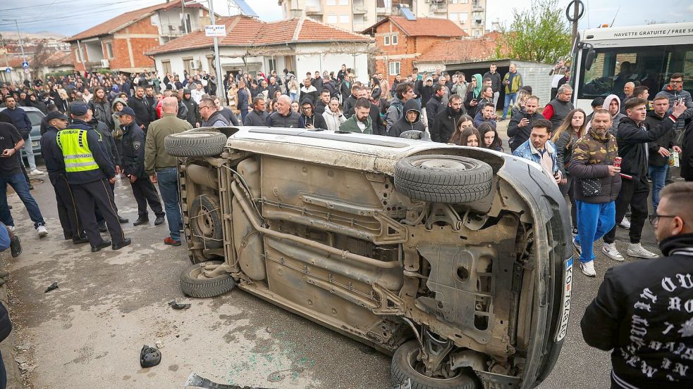 Aufgebrachte Bewohner im nordmazedonischen Kocani stürzten ein Fahrzeug des Diskothekenbesitzers um, in dessen Lokal es zu dem verheerenden Brand mit 59 Toten kam. Foto: Armin Durgut/AP/dpa