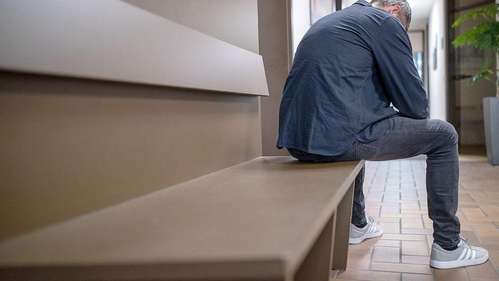 Ein Mann sitzt mit gesenktem Kopf auf einer Bank. Immer häufiger werden Männer als Opfer häuslicher Gewalt erfasst. Hilfsangebote gibt es kaum. Foto: DPA