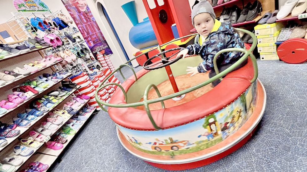 Seit dem Jahr 1962 ziert das Lurchi-Karussell die Kinderschuh-Abteilung im Schuhhaus Haltenhoff in Wiesmoor. Der zweijährige Linus aus Friedeburg gehört eher zu den vorsichtigen Mitfahrern. Foto: Ortgies