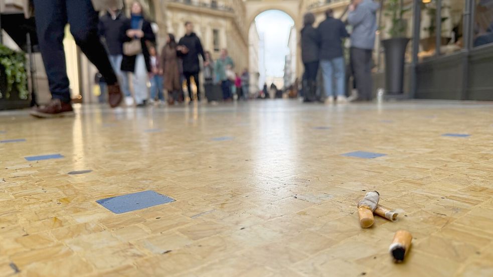 In der Viktor-Emanuel-II.-Galerie, der Einkaufspassage Galleria Vittorio Emanuele II, liegen Zigarettenkippen auf dem Boden. Foto: Christoph Sator/dpa
