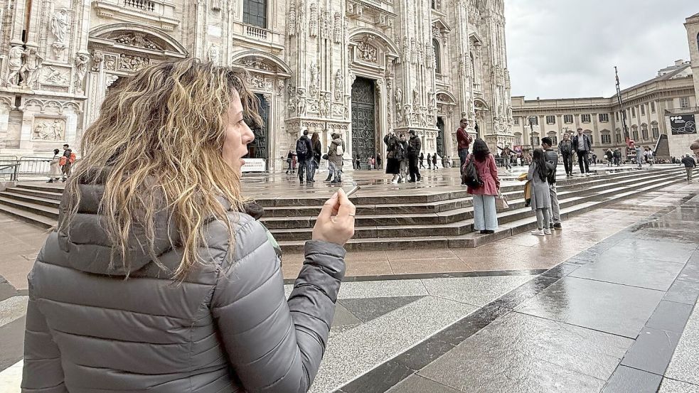 Eine Touristin mit Zigarette in der Hand vor dem Dom in Mailand. Foto: Christoph Sator/dpa