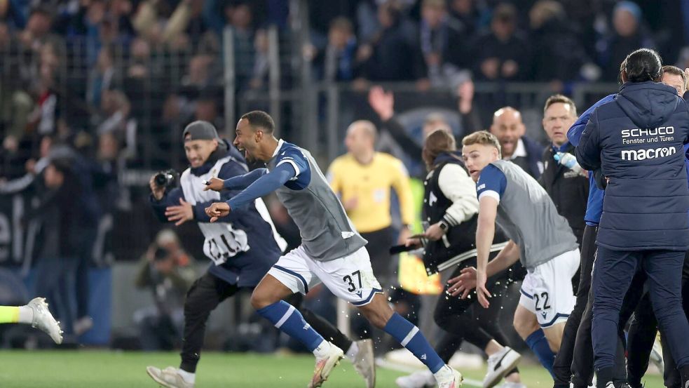 Der Moment des Siegs: Bielefelder Spieler stürmen auf den Rasen. Foto: Friso Gentsch/dpa