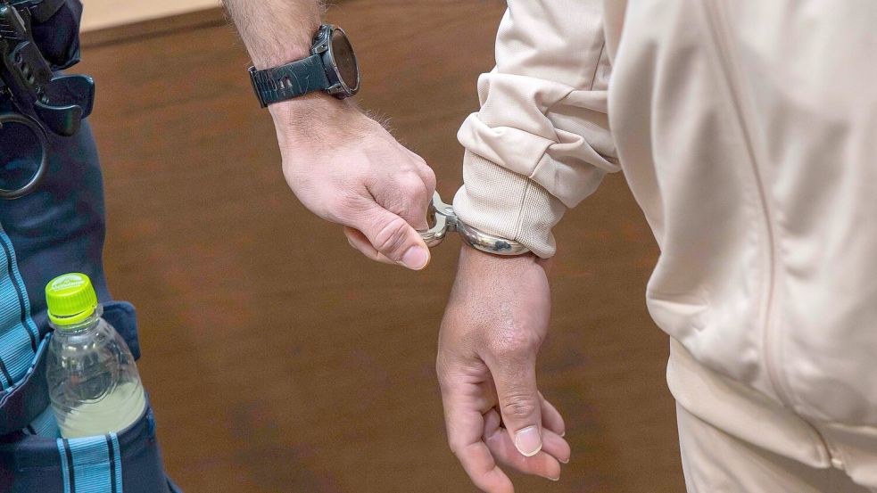 Einer der Angeklagten wird in den Gerichtssaal geführt - insgesamt sind zwölf Männer angeklagt. Foto: Peter Kneffel/dpa