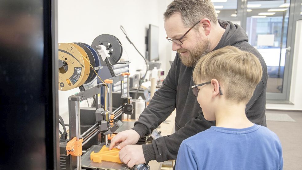 Christian Koptein, Ausbilder bei Orgadata, zeigt einem Jungen, was man mit einem 3D-Drucker machen kann. Foto: privat