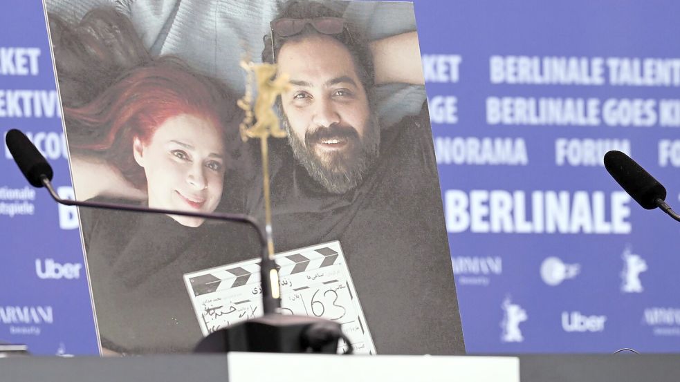 Während der Berlinale 2024 stand ein Foto der beiden Regisseure Maryam Moghaddam (links) und Behtash Sanaeeha bei der Pressekonferenz zum Film „Keyke mahboobe man“ (englischer Titel: „My Favourite Cake“) neben den leer gebliebenen Plätzen auf dem Podium. Foto: Soeren Stache/dpa
