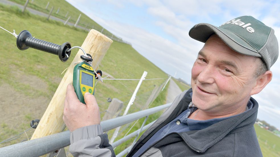 Hier fließt Strom: Deichschäfer Dennis Bonsemeyer stellt mit einem Messgerät die Spannung fest. Rund 4000 Volt fließen durch den Wolfschutzzaun. Foto: Ortgies