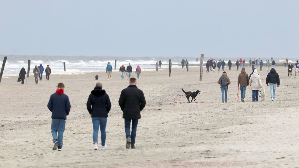 Bei Temperaturen um 10 Grad sind zahlreiche Spaziergänger am Strand der ostfriesischen Insel Norderney unterwegs. Foto: Volker Bartels/dpa