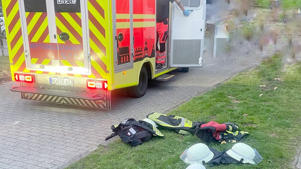 Im Inneren des Rettungswagens kämpfen Rettungsdienst und Feuerwehr gemeinsam um das Leben einer Norder Seniorin. Auf dem Rasen liegen die Einsatzjacken und Helme der Feuerwehrleute. Diese haben sie schnell ausgezogen, um bei der Reanimation effektiver helfen zu können. Foto: Freiwillige Feuerwehr Norden