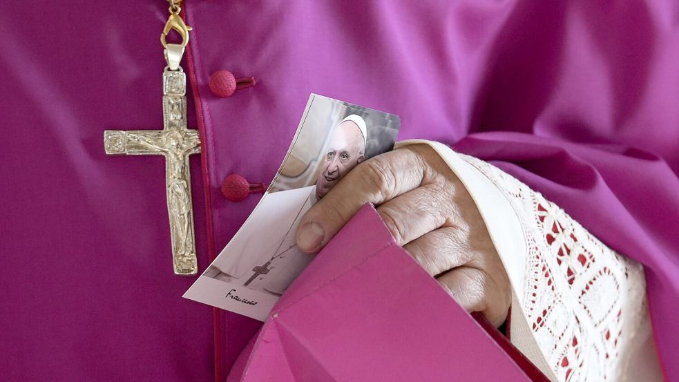 Ein Priester hält ein Bild von Papst Franziskus. Foto: Andrew Medichini/AP Pool/dpa