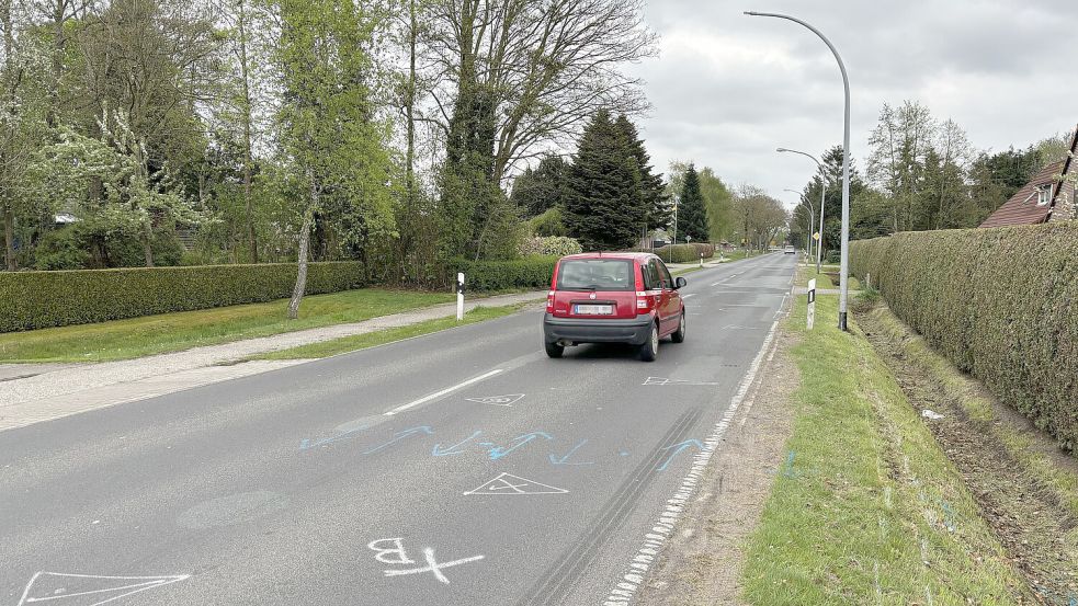 Ein Auto passiert in Halbemond die Laterne, gegen die die 17-Jährige mit ihrem Motorrad prallte. Die Polizei hat die Unfallstelle auf der Straße markiert. Foto: Thomas Dirks