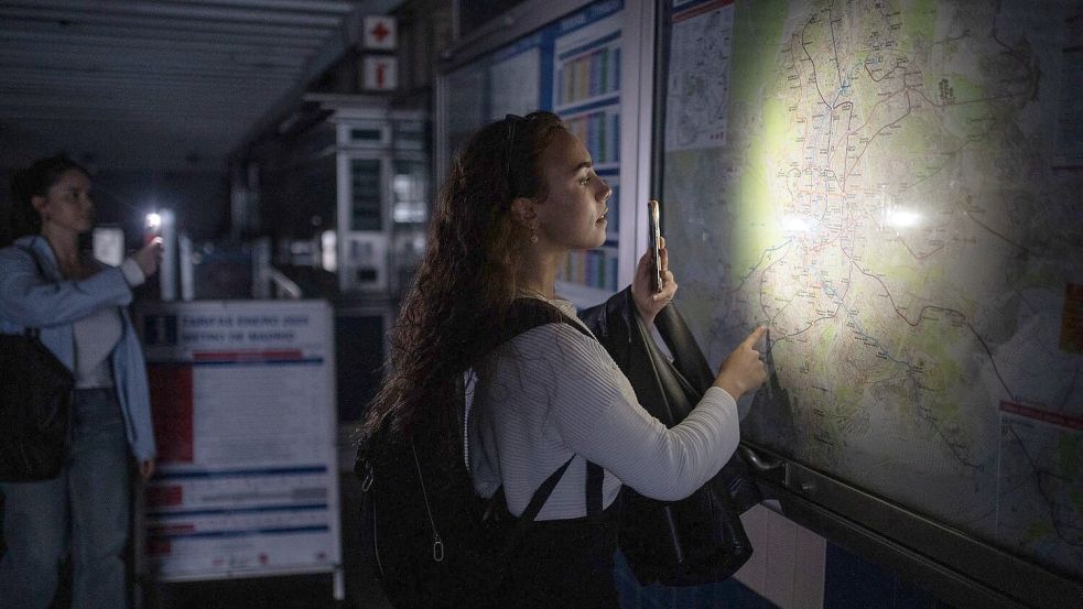 Eine Frau behilft sich mit der Taschenlampe ihres Handys, um den Plan des Madrider U-Bahn-Netzes anschauen zu können. Foto: Alejandro Martínez Vélez/EUROPA PRESS/dpa