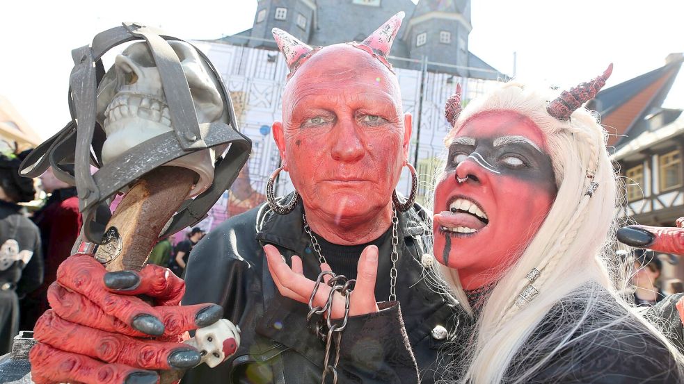 Im Teufelskostüm stehen Besucher auf dem Marktplatz in Wernigerode. Foto: Matthias Bein/dpa