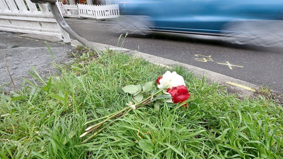 Am Tag nach dem Unfall liegen Rosen am Straßenrand. Foto: Bernd Weißbrod/dpa