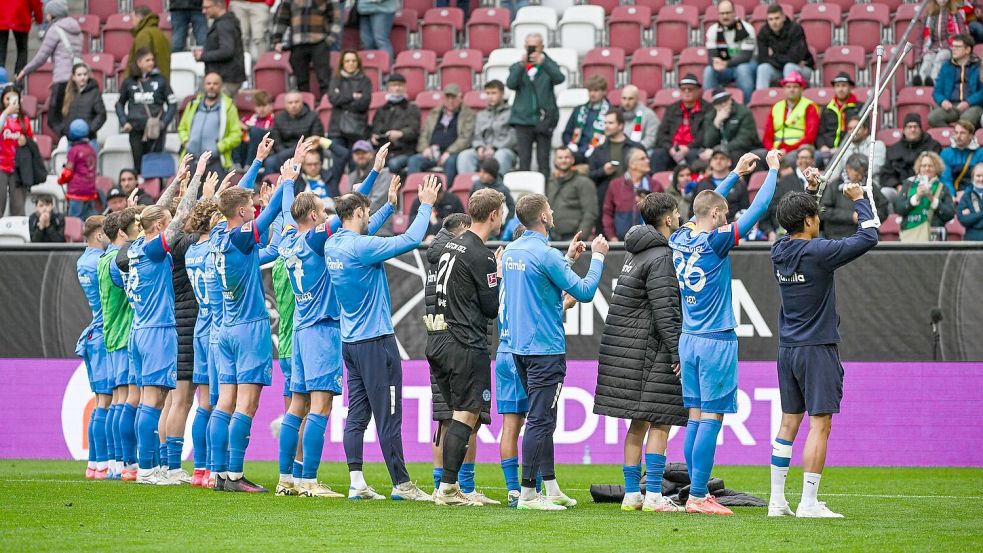 Holstein Kiel feiert den Sieg in Augsburg mit den mitgereisten Fans Foto: Armin Weigel/dpa