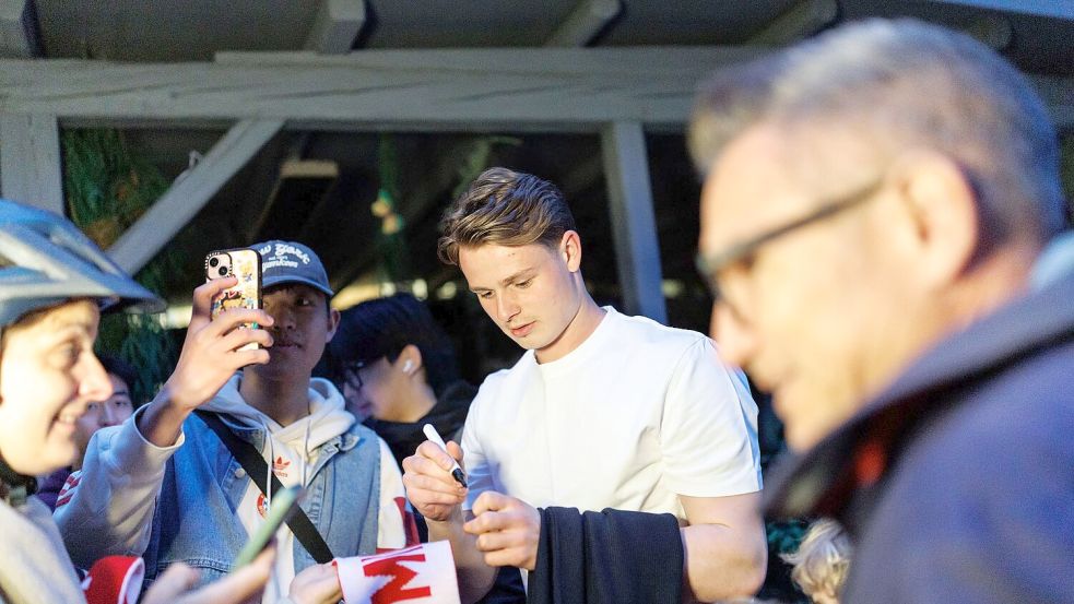 Torhüter Jonas Urbig schreibt Autogramme, bevor er mit seinen Teamkollegen feiert. Foto: Matthias Balk/dpa