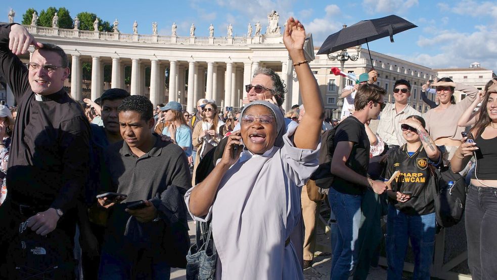 Gläubige telefonieren mit ihren Angehörigen, um vom neuen Papst zu berichten. Foto: Emilio Morenatti/AP/dpa