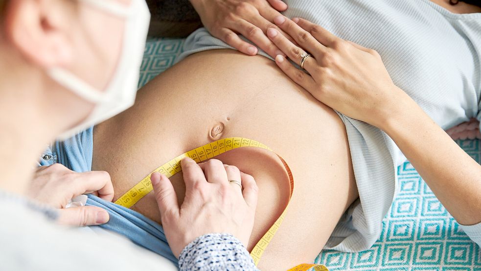 Eine Hebamme misst bei einer Schwangeren in diesem Symbolbild den Symphyse-Fundus-Abstand, um die Größe der Gebärmutter und des Kindes im Mutterleib einzuschätzen. Foto: DPA