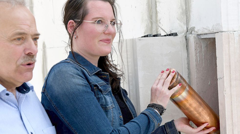 Viola Feldmann schiebt die Röhre in die Wand, Uwe Themann spricht zu den Gästen. Foto: Stromann
