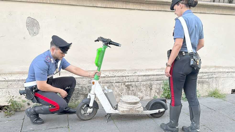 Zwei Carabinieri begutachten den Marmorsockel auf einem elektrischen Leihroller. Foto: ---/Comando Generale Dell’arma D