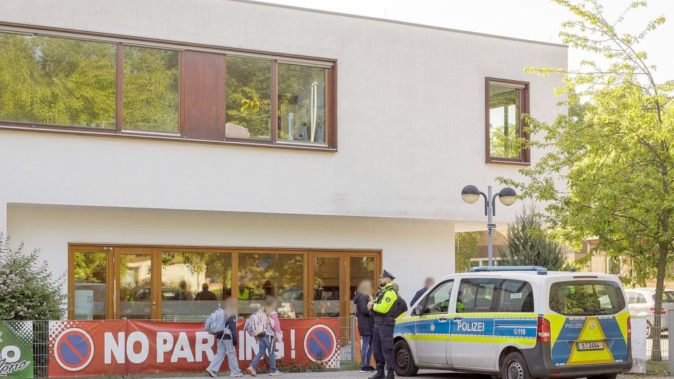 Die Polizei steht vor einer Grundschule im Berliner Bezirk Spandau, während Schüler am Morgen zur Schule kommen. Foto: Julius-Christian Schreiner/dpa
