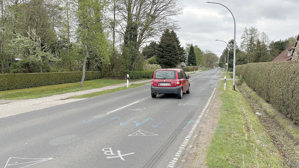 Ein Auto passiert in Halbemond die Laterne, gegen die die 17-Jährige mit ihrem Motorrad prallte. Die Polizei hat die Unfallstelle auf der Straße markiert. Foto: Thomas Dirks