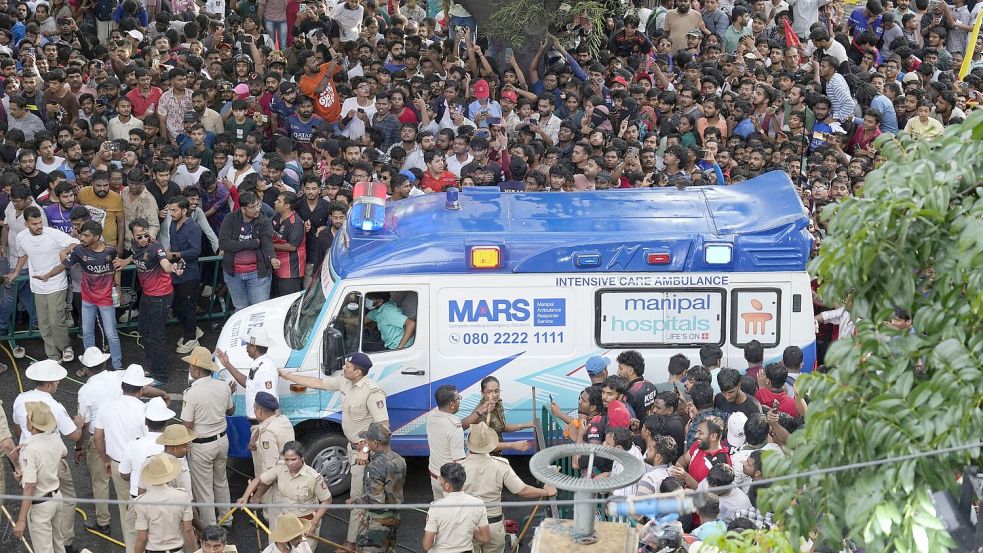 Ein Krankenwagen bahnt sich den Weg durch eine Menschenmenge am M. Chinnaswamy-Stadion in der indischen Stadt Bengaluru. Foto: Aijaz Rahi/AP/dpa