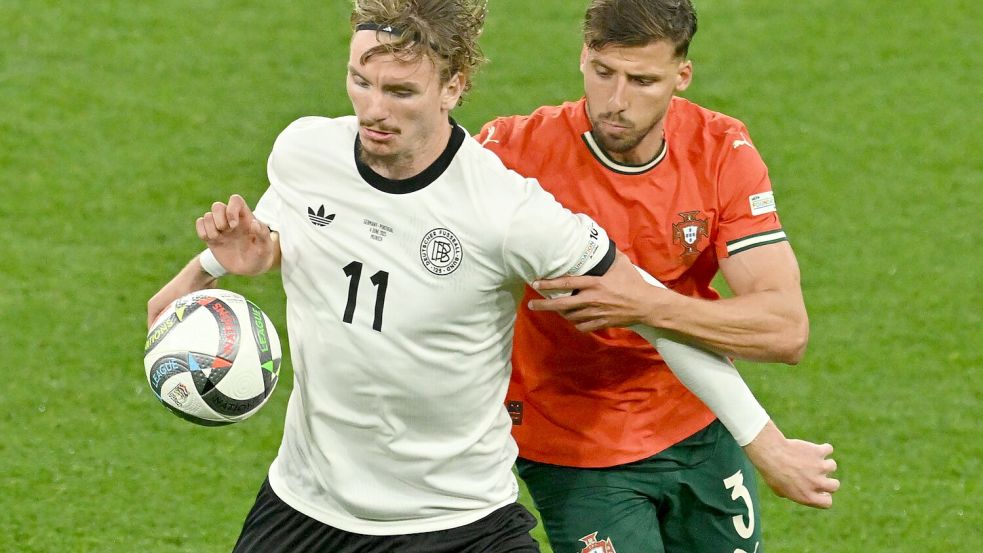 Nick Woltemade (l) hatte bei seinem Länderspiel-Debüt gegen Portugals Abwehrrecken einen schweren Stand. Foto: Peter Kneffel/dpa
