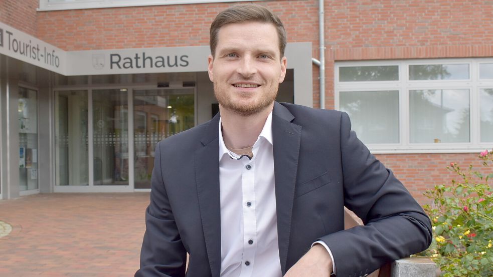 Michael Quappe sitzt auf einer Bank vor dem Ostrhauderfehner Rathaus. Der 38-Jährige möchte nach der Kommunalwahl 2026 als neuer Bürgermeister die Verwaltung leiten. Foto: Henrik Zein