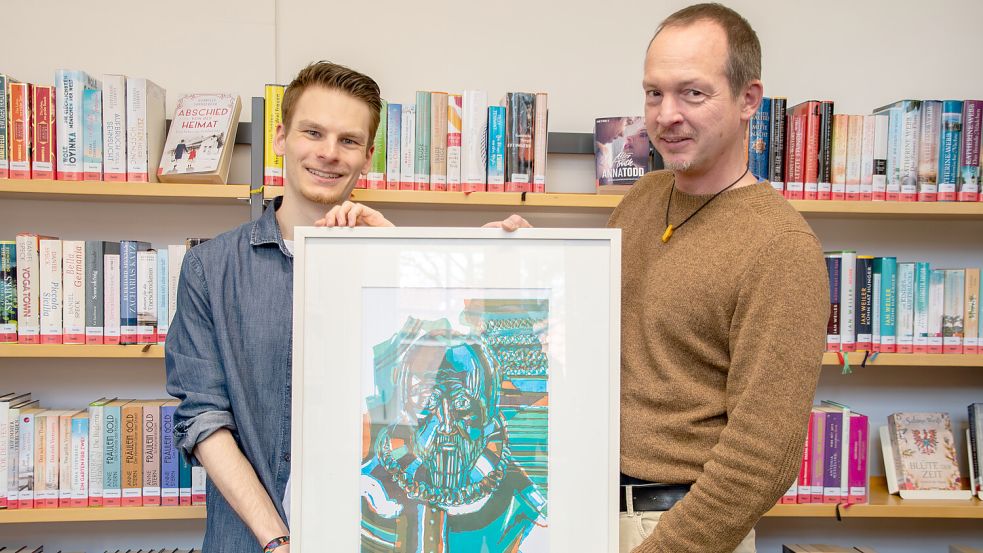 Aleksej Altrock (li.) und Dr. Welf-Gerrit Otto zeigen das erste in der Stadtbibliothek Aurich ausgestellte Bild mit Ubbo Emmius von Uwe P. Schierholz. Foto: Privat