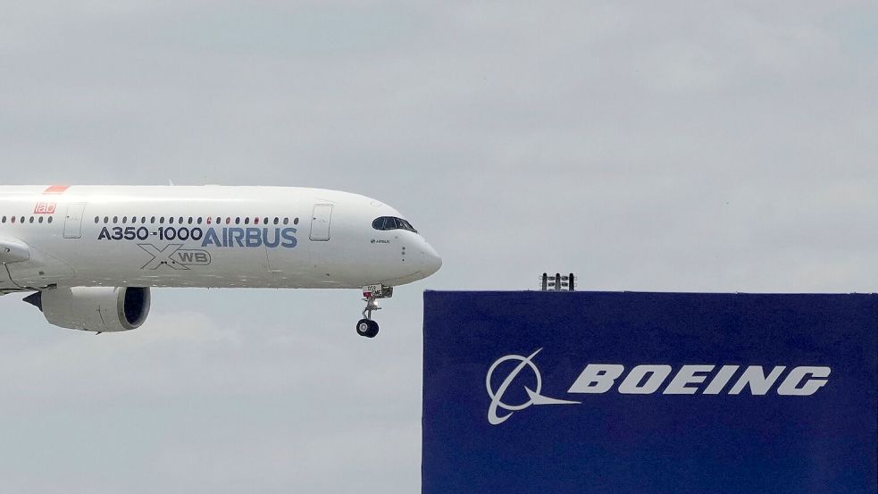 Die zwei großen Konkurrenten: Ein Airbus fliegt bei einer Vorführung auf der Luftfahrtmesse Salon du Bourget an einem Logo von Boeing vorbei. Foto: Michel Euler/AP/dpa
