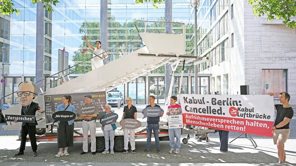 Aktivsten stehen während einer symbolischen Protestaktion am Weltflüchtlingstag zur Unterstützung mehrerer Klagen von Afghanen gegen die Bundesregierung vor dem Auswärtigen Amt. Foto: Michael Brandt/dpa