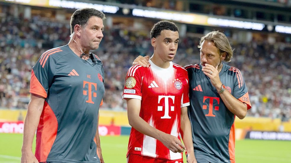 Jamal Musiala musste nur 25 Minuten nach seiner Einwechselung angeschlagen vom Platz, begleitet von Teamarzt (r) und Physiotherapeut. Foto: Sven Hoppe/dpa