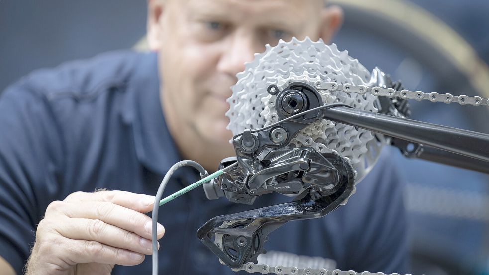 Ein Mann justiert die Ritzel an einer Fahrradschaltung auf der Ausstellungsfläche an einem Messestand auf der Fahrrad-Fachmesse Eurobike. Foto: Boris Roessler/dpa