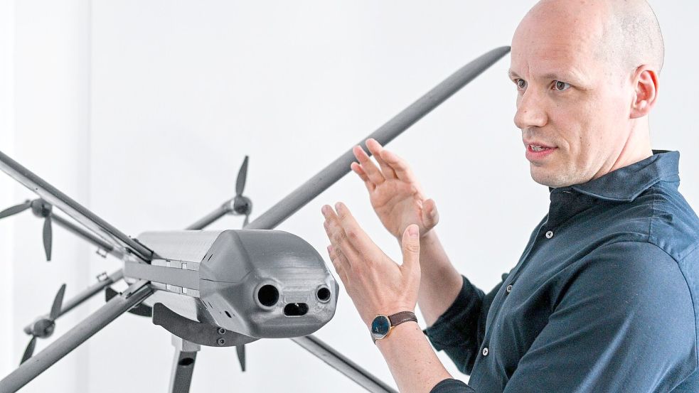 Ein Modell der HX-2-Drohne von Helsing, daneben der Mitgründer und Co-Firmenchef Gundbert Scherf. Foto: Jens Kalaene/dpa
