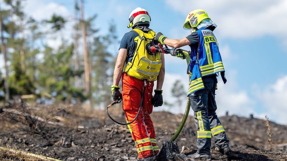 Mit Löschrucksäcken gehen die Feuerwehrleute etwa gegen Glutnester vor. Foto: Jacob Schröter/dpa