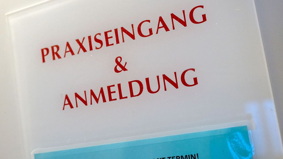Ein Schild an einer Hauswand weist auf den Eingang einer Arztpraxis hin. Foto: DPA